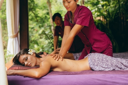 Massage therapist massaging woman at outdoor spa