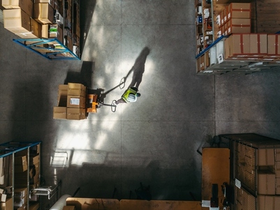 Overhead shot of a warehouse worker pulling a pallet truck