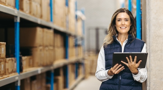 Warehouse manager smiling at the camera while holding a tablet
