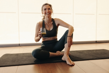 Happy senior woman having green juice while working out