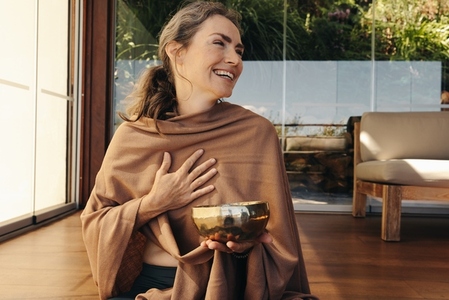 Cheerful senior woman smiling happily while holding a singing bowl