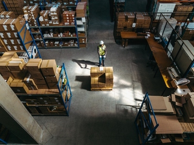 High angle view of a warehouse worker pushing a pallet truck