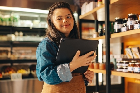 Supermarket employee with Down syndrome holding a digital tablet
