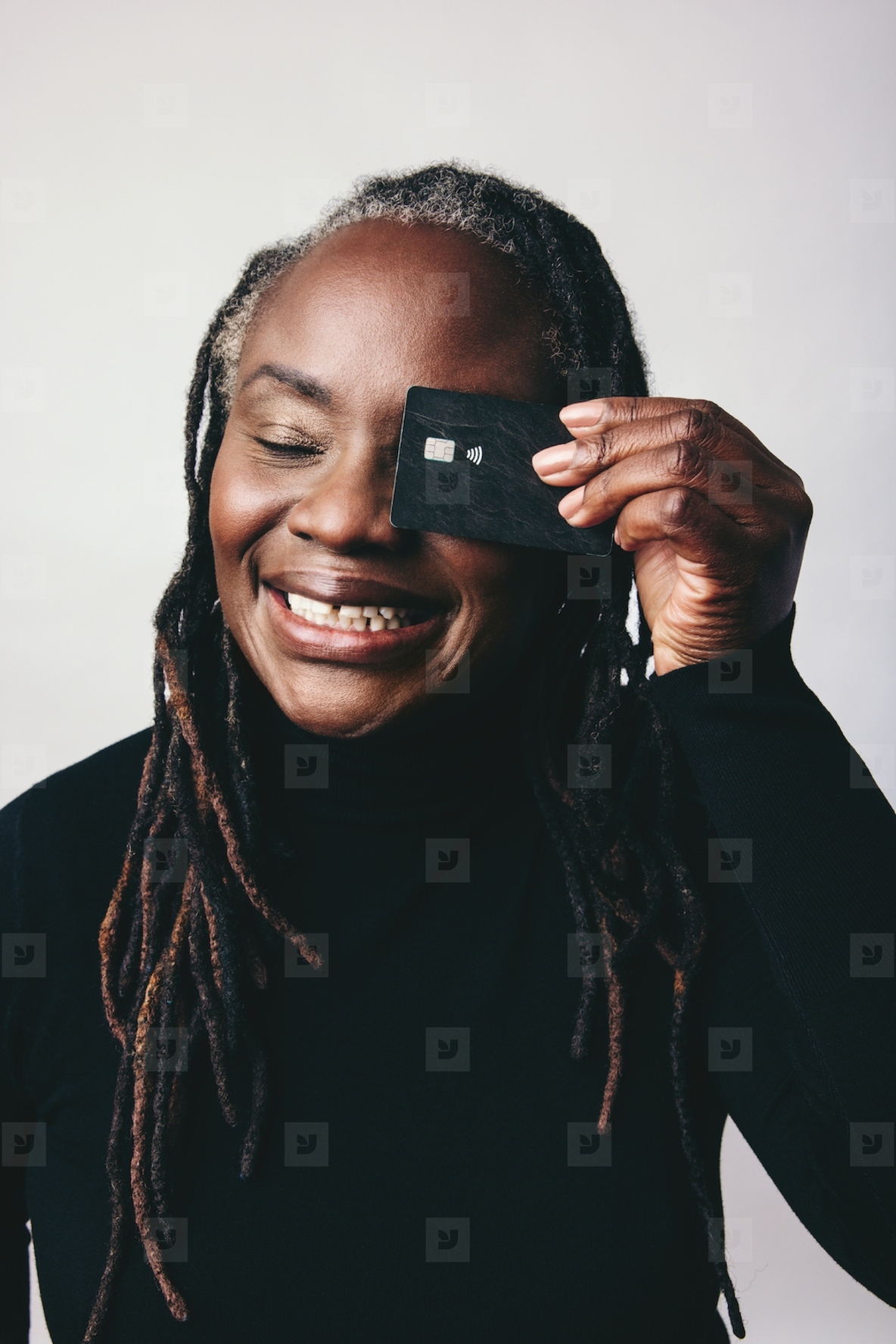 Happy woman with dreadlocks holding a credit card over her eye