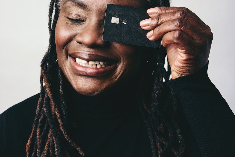 Happy woman with dreadlocks holding a credit card over her eye
