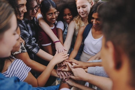 Diverse teenagers putting their hands together in unity