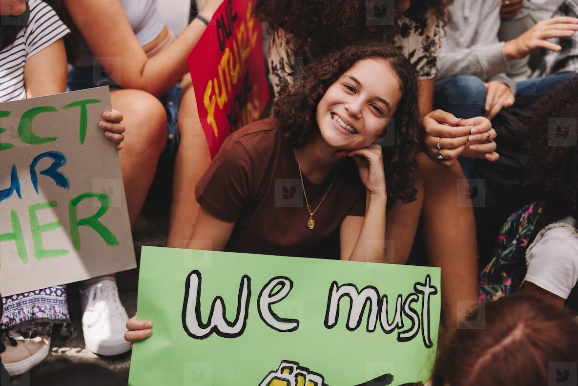 Cheerful teenage girl sitting with a group of climate activists