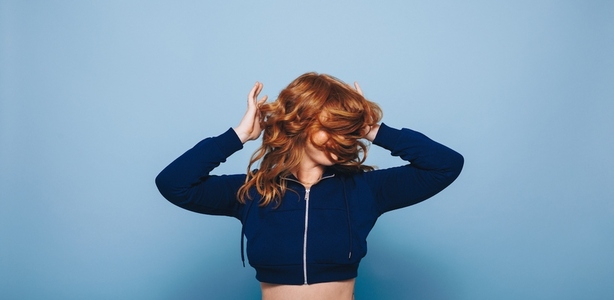 Woman in a crop top flipping her ginger hair cheerfully