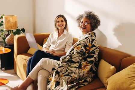 Cheerful businesswomen sitting on a couch in a modern office