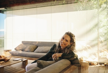 Happy mature woman smiling at the camera while sitting on a couch
