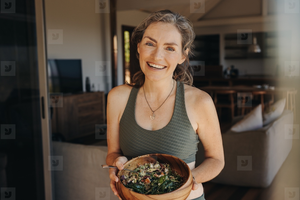 Cheerful vegan woman eating a vegetable salad from a bowl