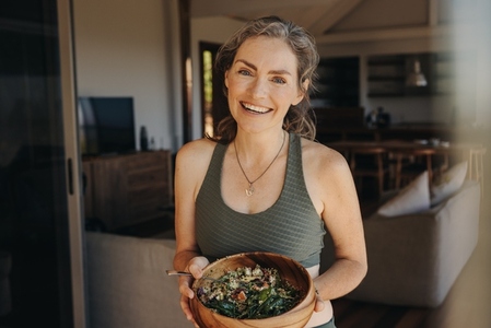 Cheerful vegan woman eating a vegetable salad from a bowl