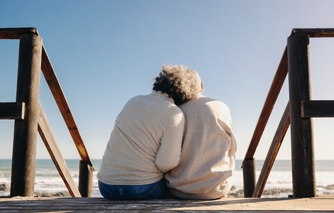 Senior couple sitting on a wooden foot bridge at the beach