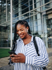 Happy young business woman using a smartphone while commuting in the city