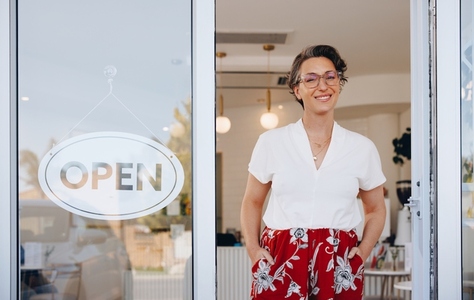 Mature woman smiling while standing at the doorway of her newly opened restaurant