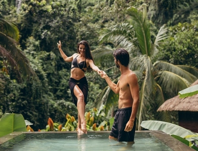 Man helping girlfriend entering the pool at resort