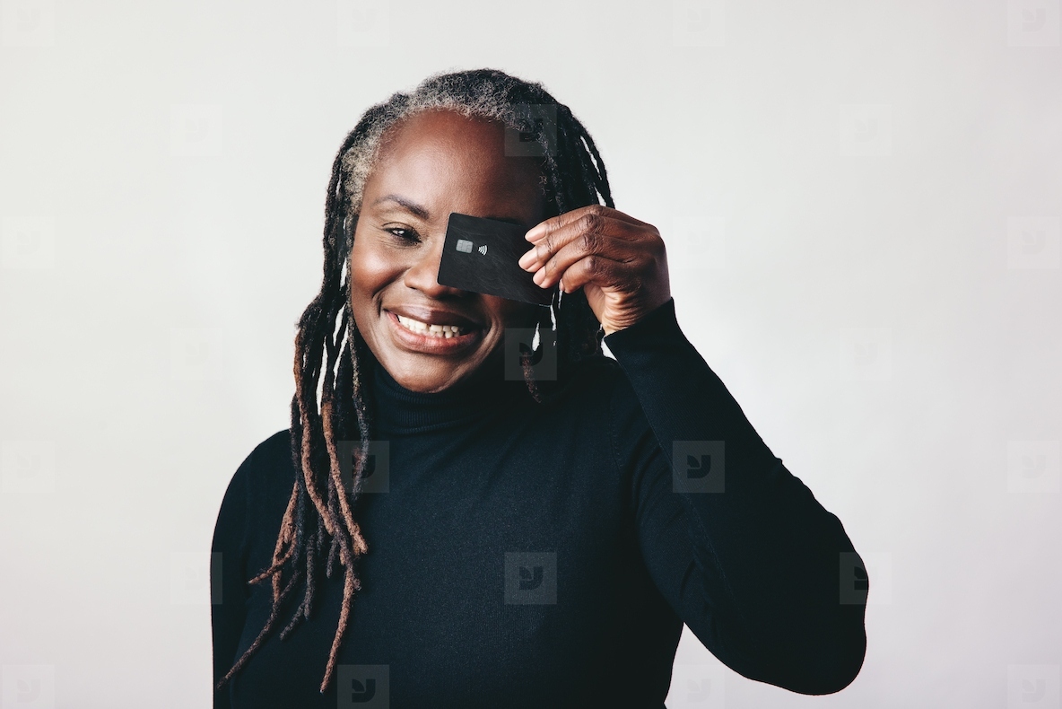 Happy mature woman smiling at the camera while holding a credit card