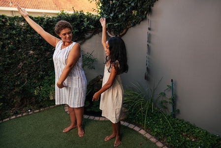 Girl and her granny practicing dance moves together at backyard