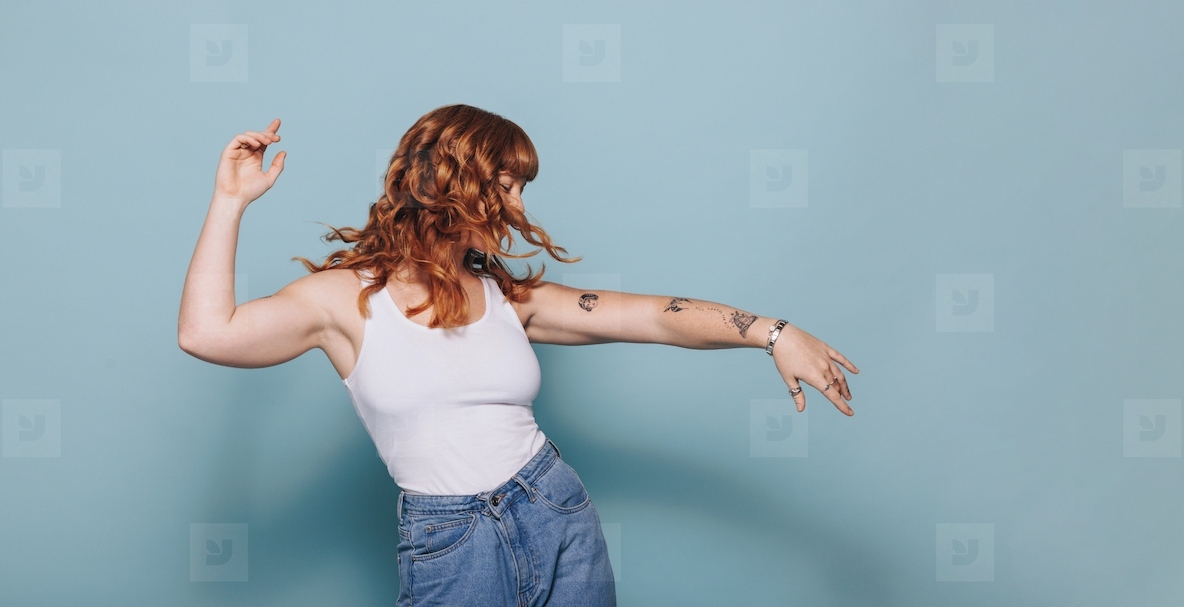 Red haired woman dancing in a studio