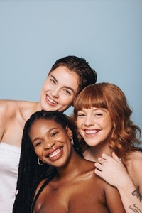Happy women with different skin tones smiling at the camera in a studio