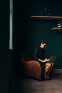 Businesswoman in armchair working on laptop