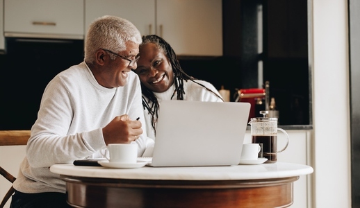 Cheerful senior couple using a laptop together at home