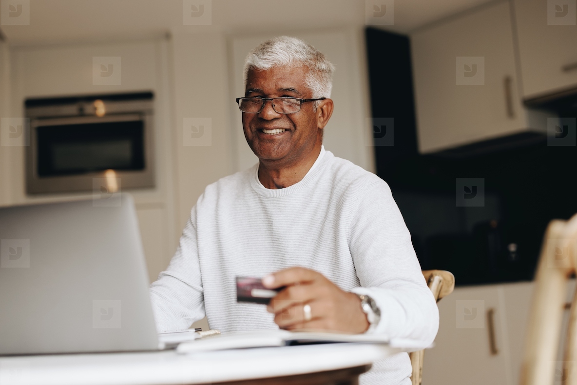 Happy senior man shopping online at home