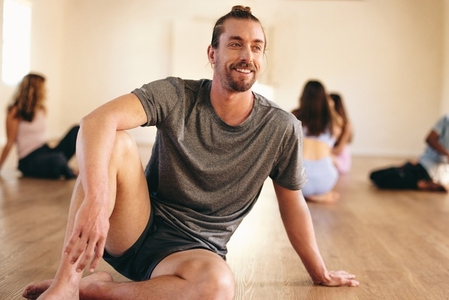 Happy young man sitting in a yoga class