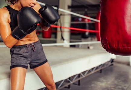 Sporty young woman working out with a red punching bag