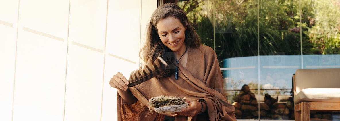 Happy senior woman preparing to burn sage with a feather at home