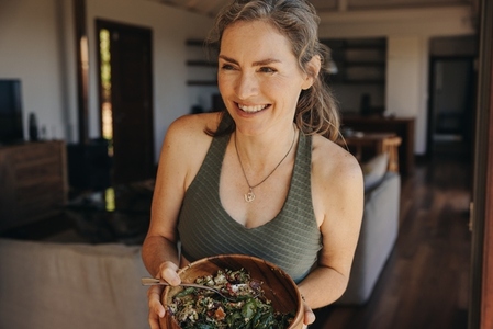 Fit senior woman smiling while holding a buddha bowl