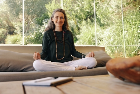 Happy holistic healer meditating in her living room