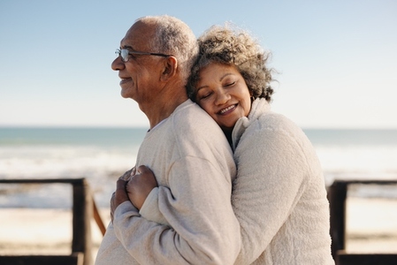 Affectionate senior woman embracing her husband at the beach