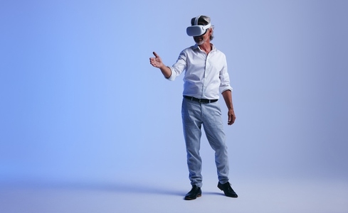 Mature businessman giving a virtual handshake in a studio
