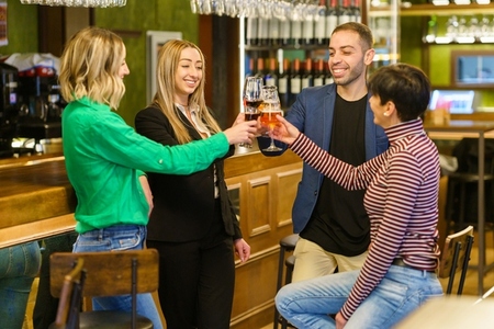 Cheerful men and women toasting at a bar counter