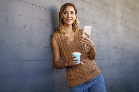 Stylish female with coffee browsing cellphone
