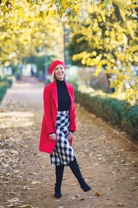 Cheerful woman standing in autumn park