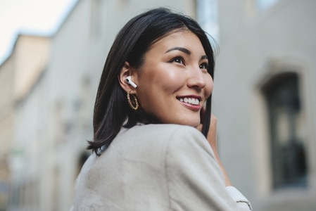 Business woman standing in a street with earphones