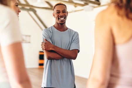 Happy young man smiling at the camera while standing in a yoga class