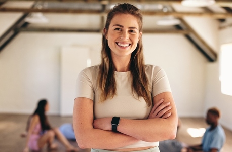 Woman smiling at the camera while standing in a yoga class
