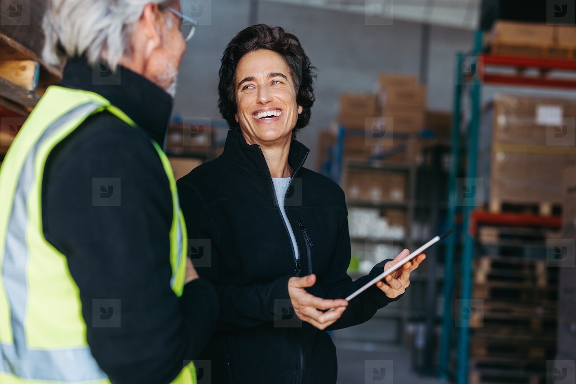 Female warehouse supervisor smiling at her colleague during a discussion