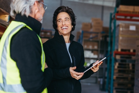 Female warehouse supervisor smiling at her colleague during a discussion