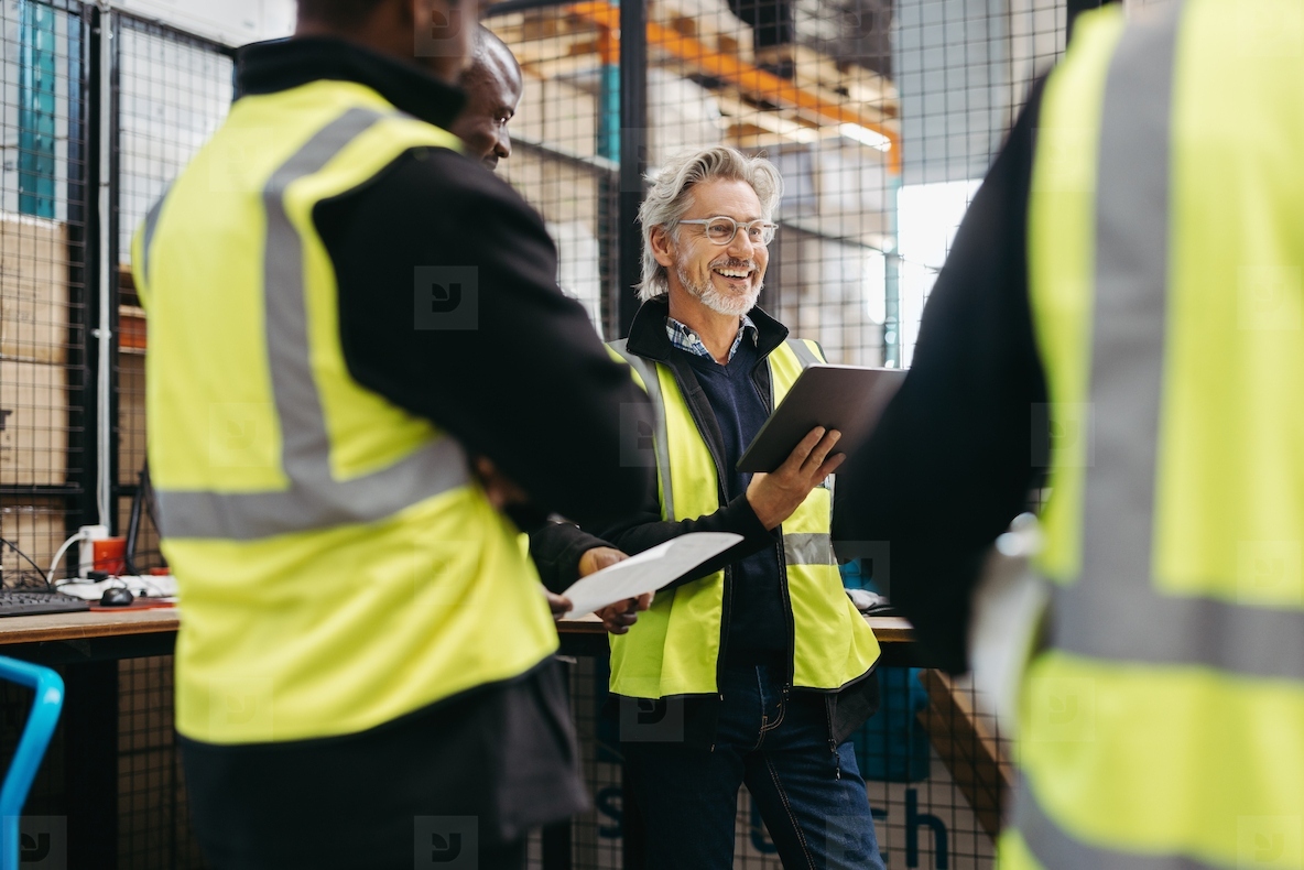 Mature warehouse manager having a meeting with his team