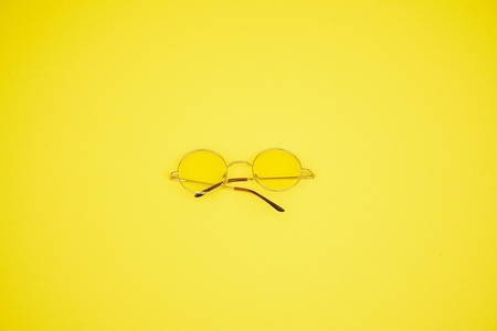 Minimal image of retro yellow sunglasses against yellow backgrou