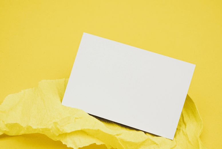 Blank business card over a yellow crepe paper against yellow bac