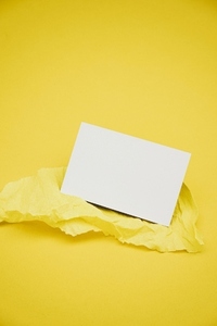 Blank business card over a yellow crepe paper against yellow bac