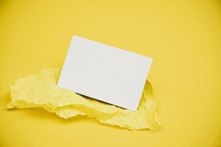 Blank business card over a yellow crepe paper against yellow bac
