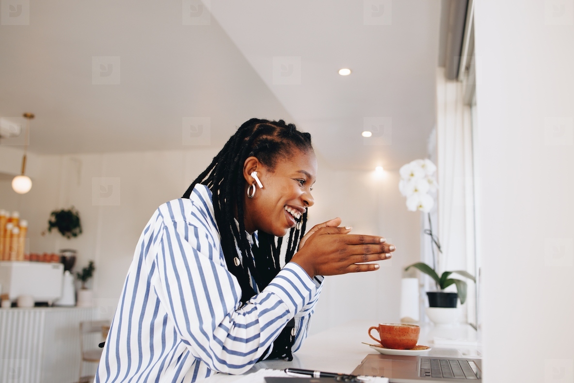 Smiling black businesswoman having a virtual meeting with a client in a cafe