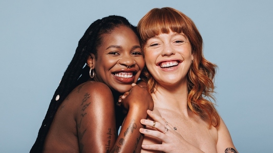 Two women with different skin tones smiling at the camera