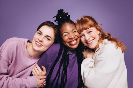 Portrait of happy female friends smiling at the camera in a studio